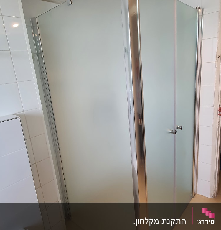 מקלחון זכוכית עם דלתות מתכת בחדר אמבטיה